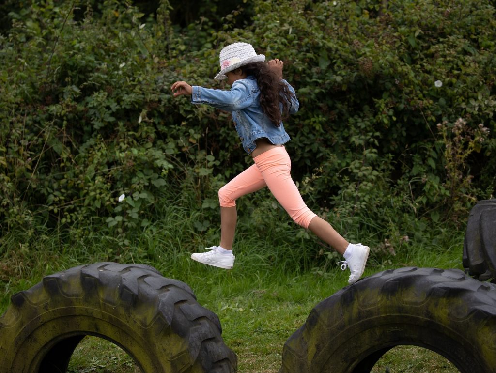 girl jumping from a large tyre to another in a fun exercise game